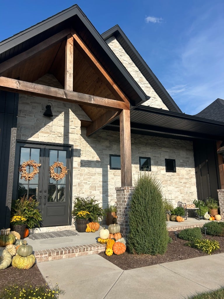 Autumn wreaths on the black double doors of a stone home