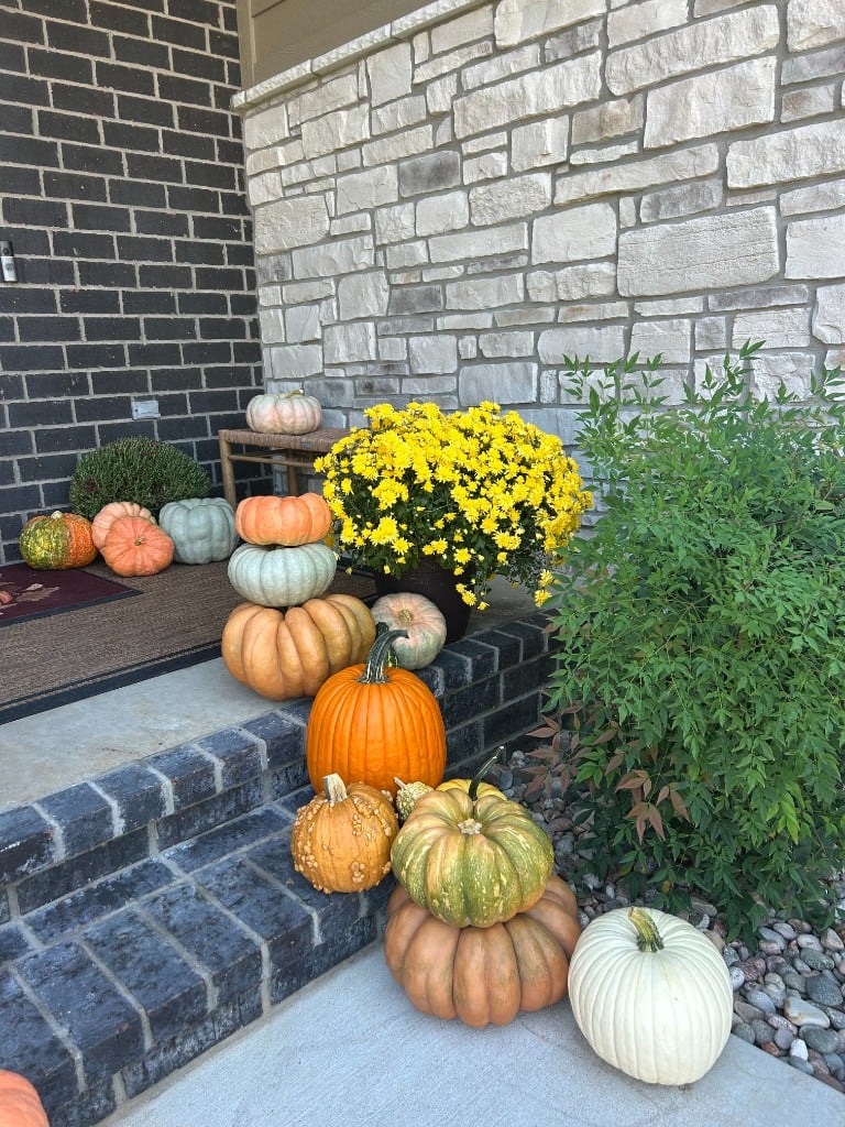Yellow mums and stacked heirlooms on a stone and brick landing